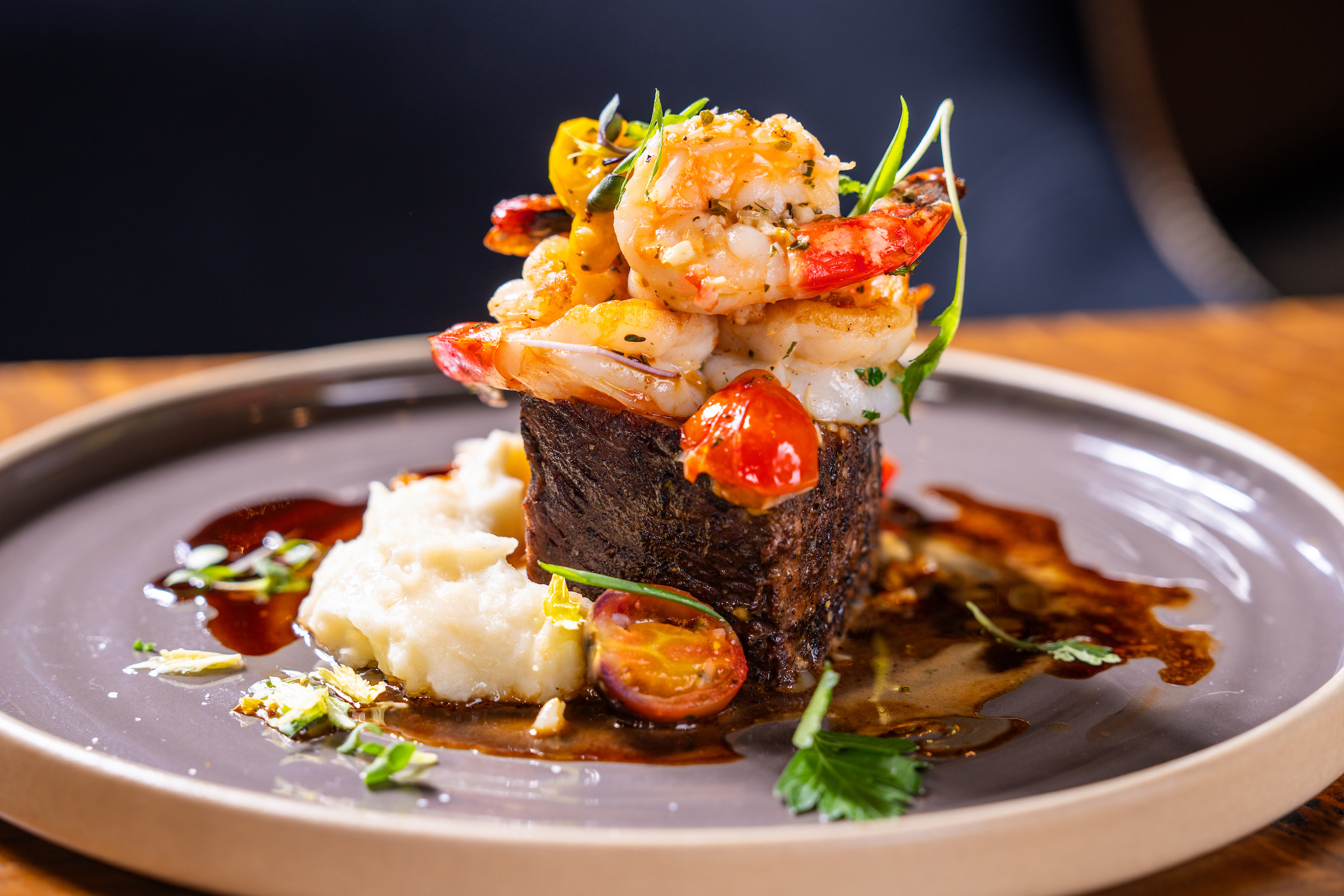 Steak and potatoes topped with shrimp.