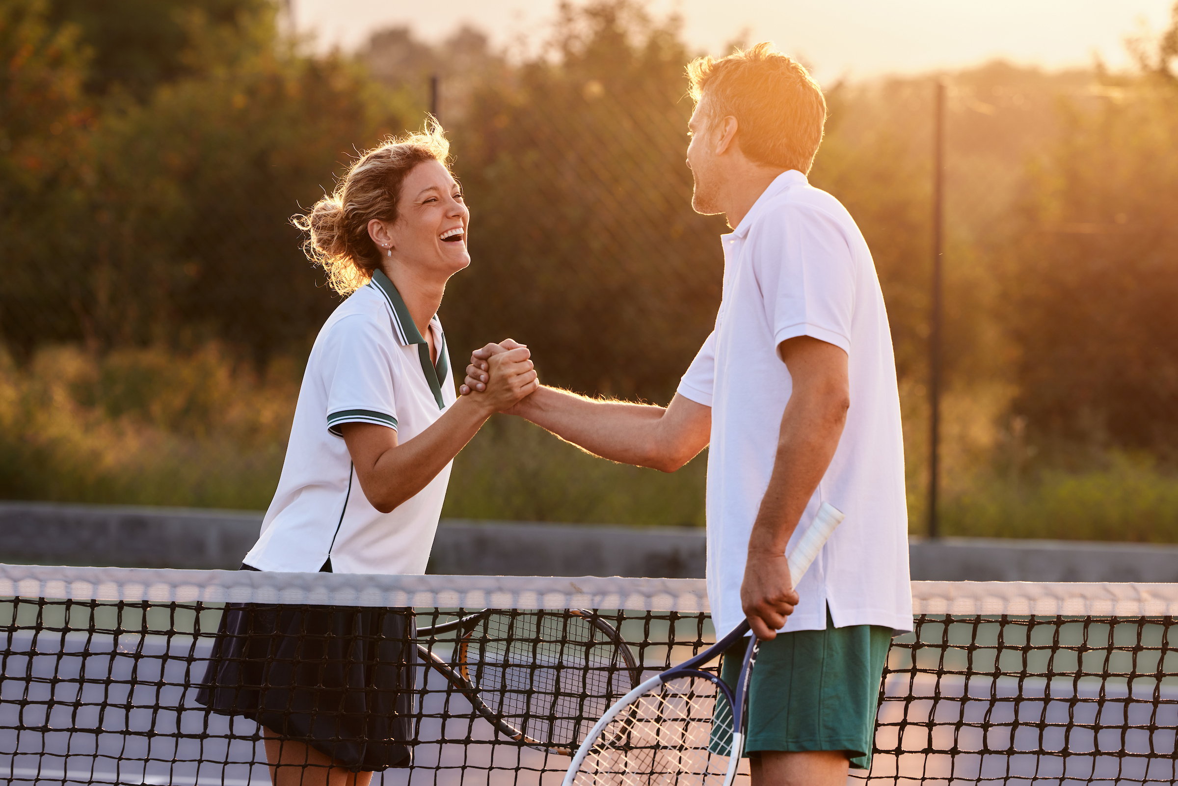 Girl and guy playing tennis and shaking hands afterwards.